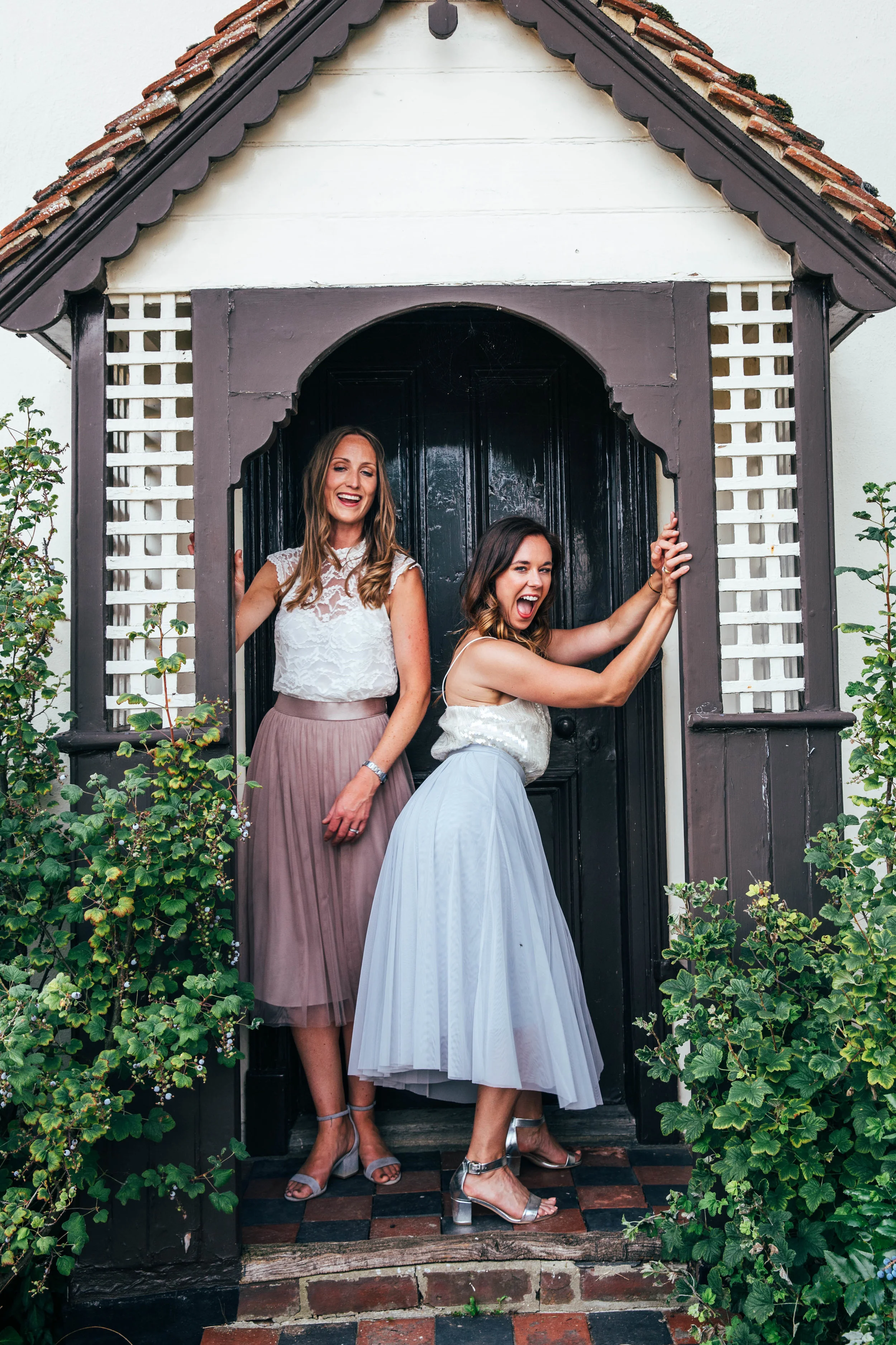 Laughing wedding guests in doorway for DIY Boho wedding. Essex Documentary Wedding Photographer