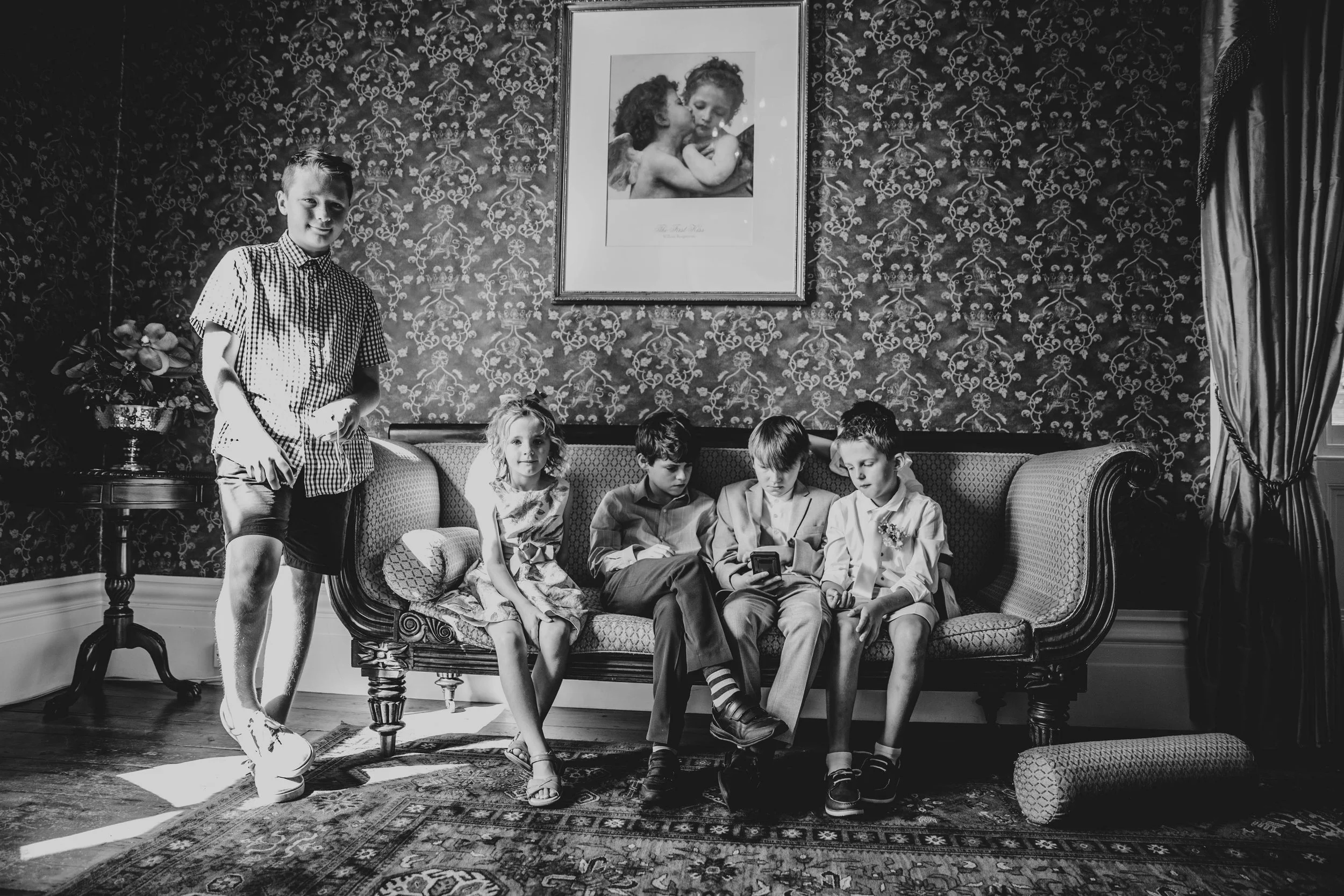 Children wedding guests look at phones.  Fennes, Braintree.  Essex Documentary Wedding Photographer