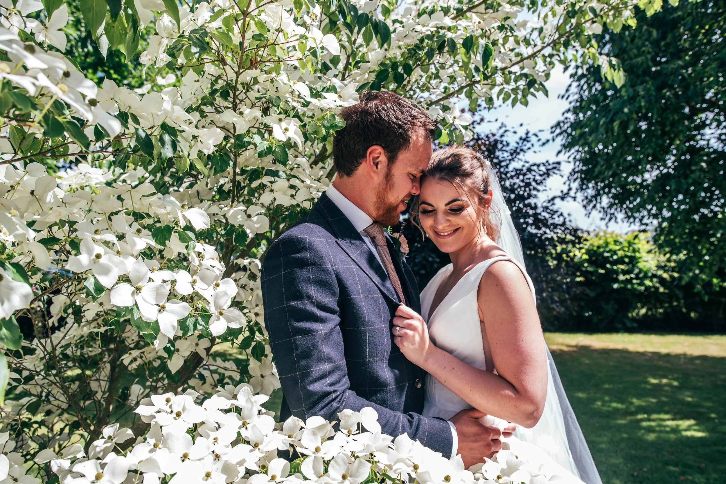 Bride and Groom by white flowered bush at Ratsbury Barn, Essex Documentary Wedding Photographer