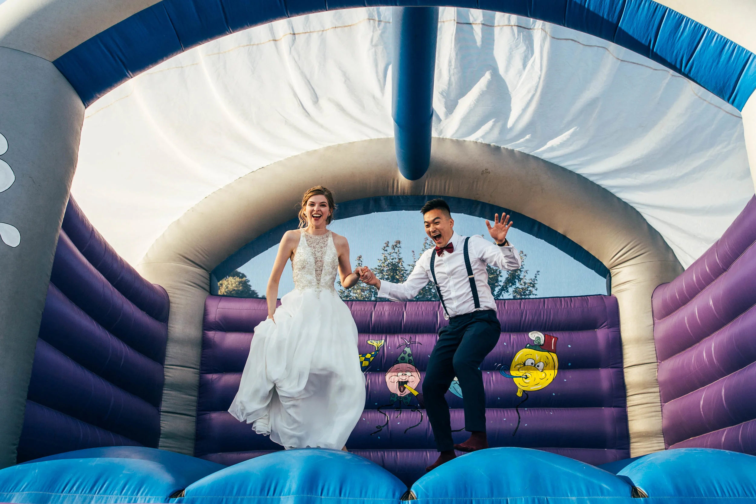 Bride and Groom jump on Bouncy Castle at The Long Barn, Essex Documentary Wedding Photographer 