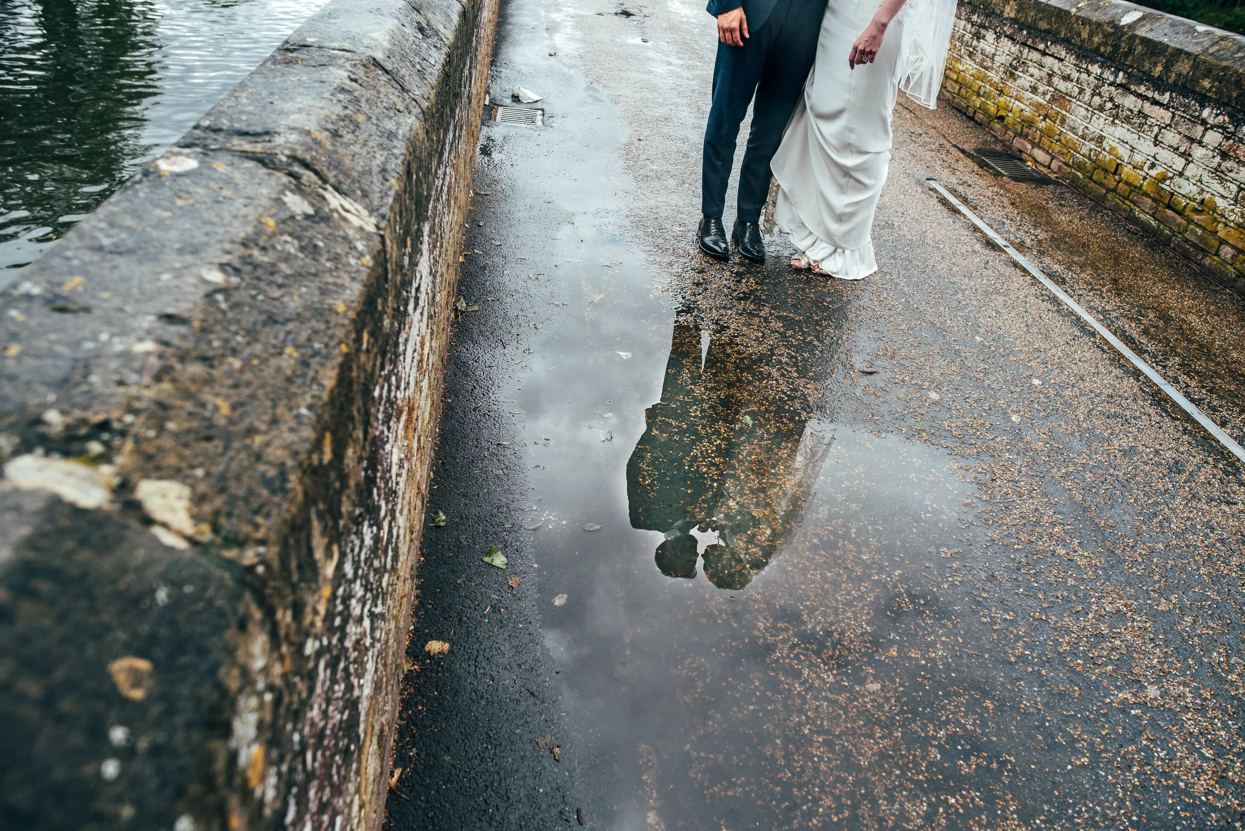 Bride and Groom reflection in puddle on rainy wedding, Essex Documentary Wedding Photographer