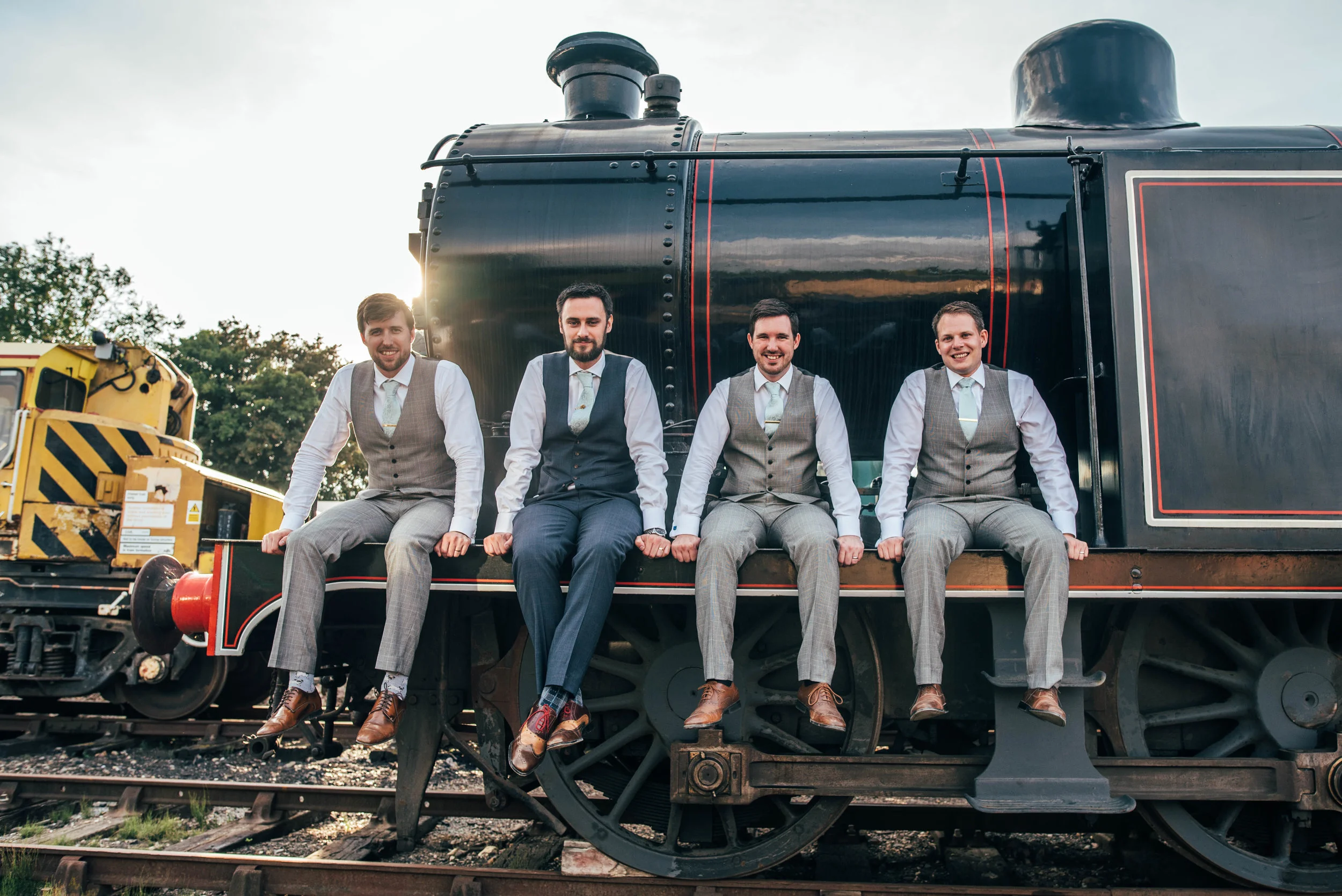 Groom and Groomsmen sit on train at East Anglian Railway Museum, Essex Documentary Wedding Photographer