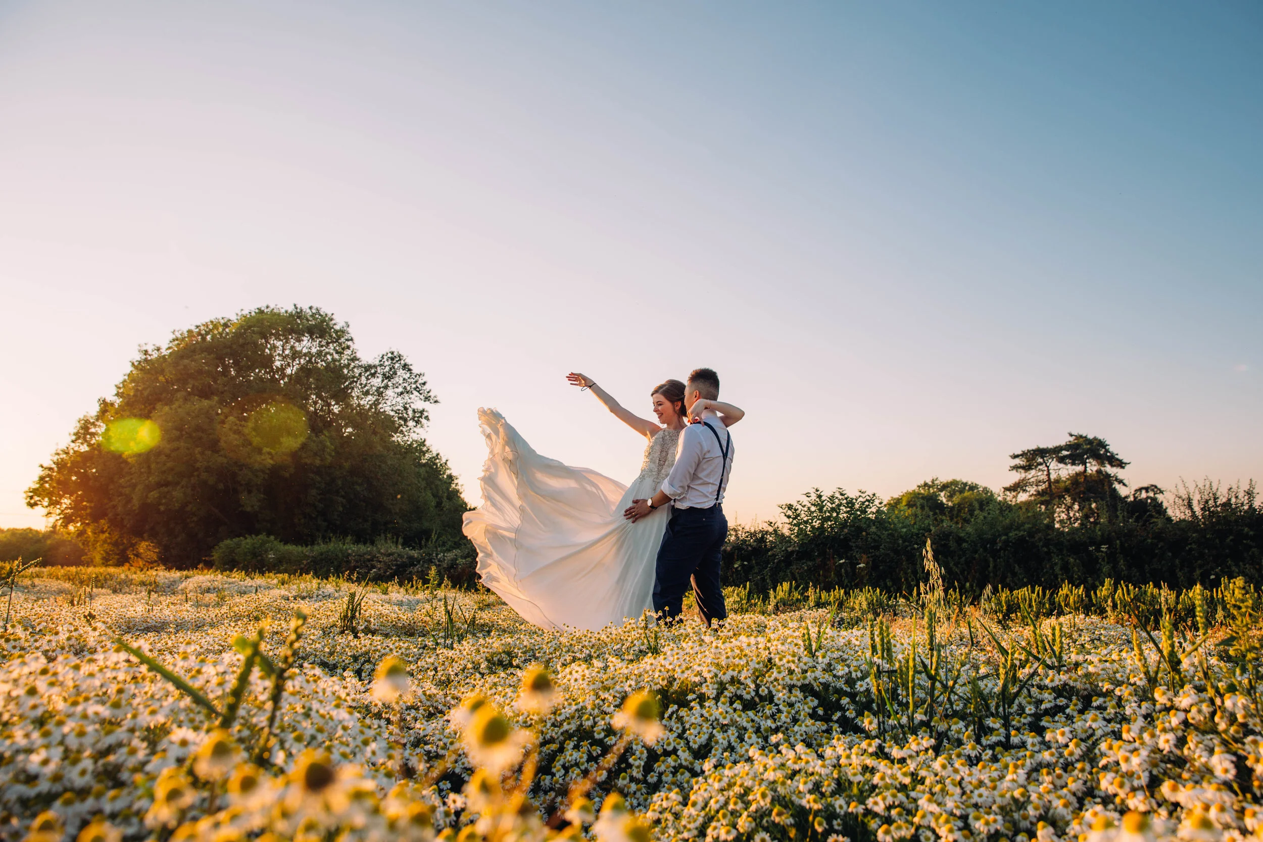 Bride wafts her dress in yellow field at sunset, The Long Barn, Essex Documentary Wedding Photographer
