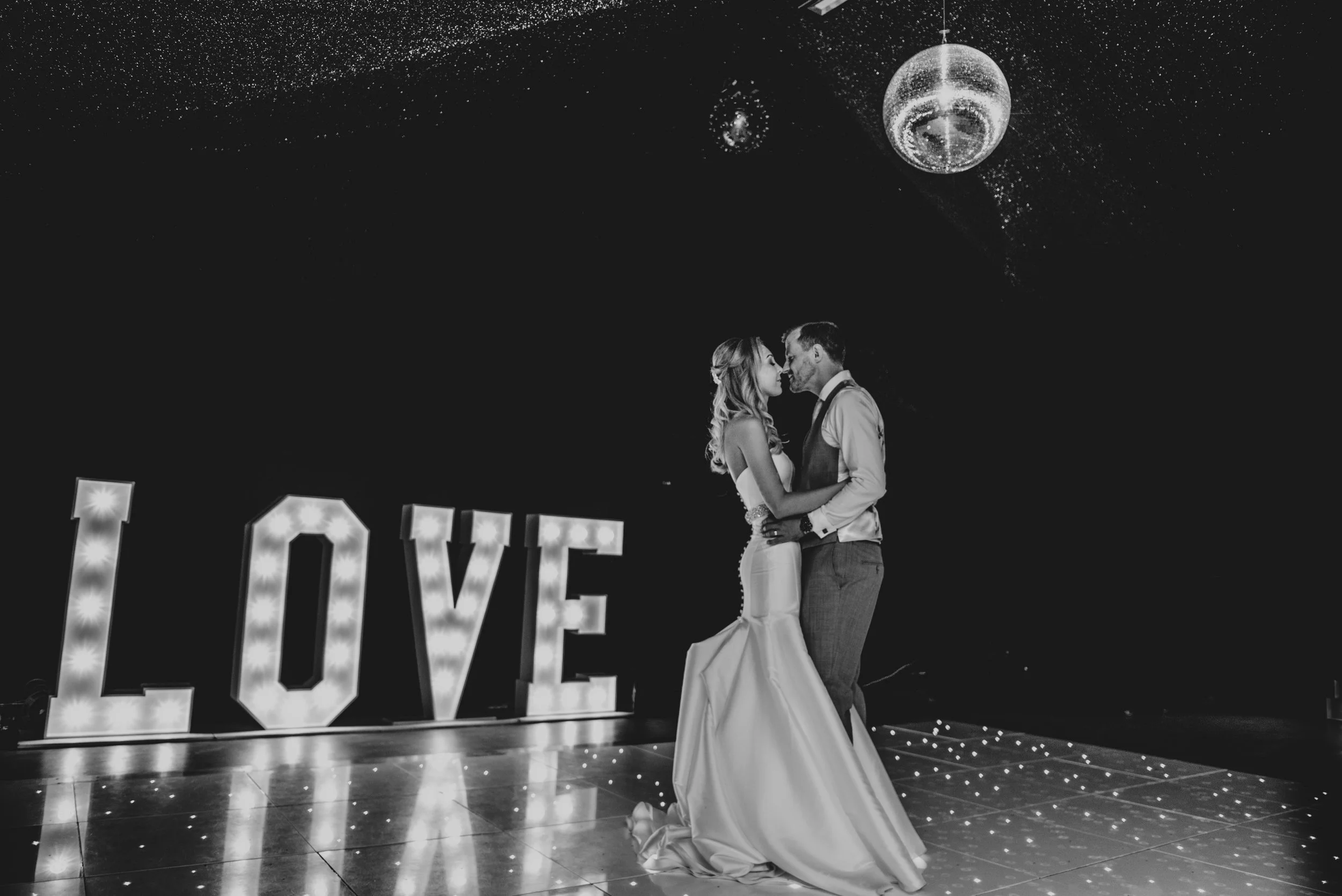 Bride & Groom with glitter ball and marquee love lights have first dance at Fennes Braintree Essex documentary wedding Photographer
