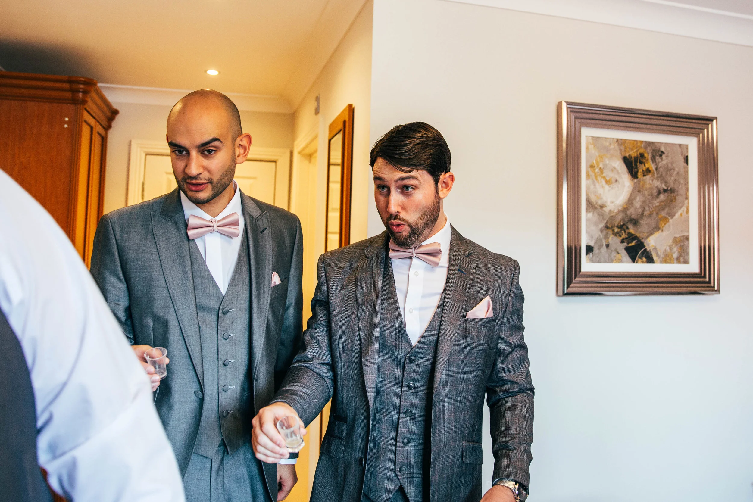 Groom pulls grimacing face after taking a shot at Blake Hall wedding Essex Documentary Wedding Photographer