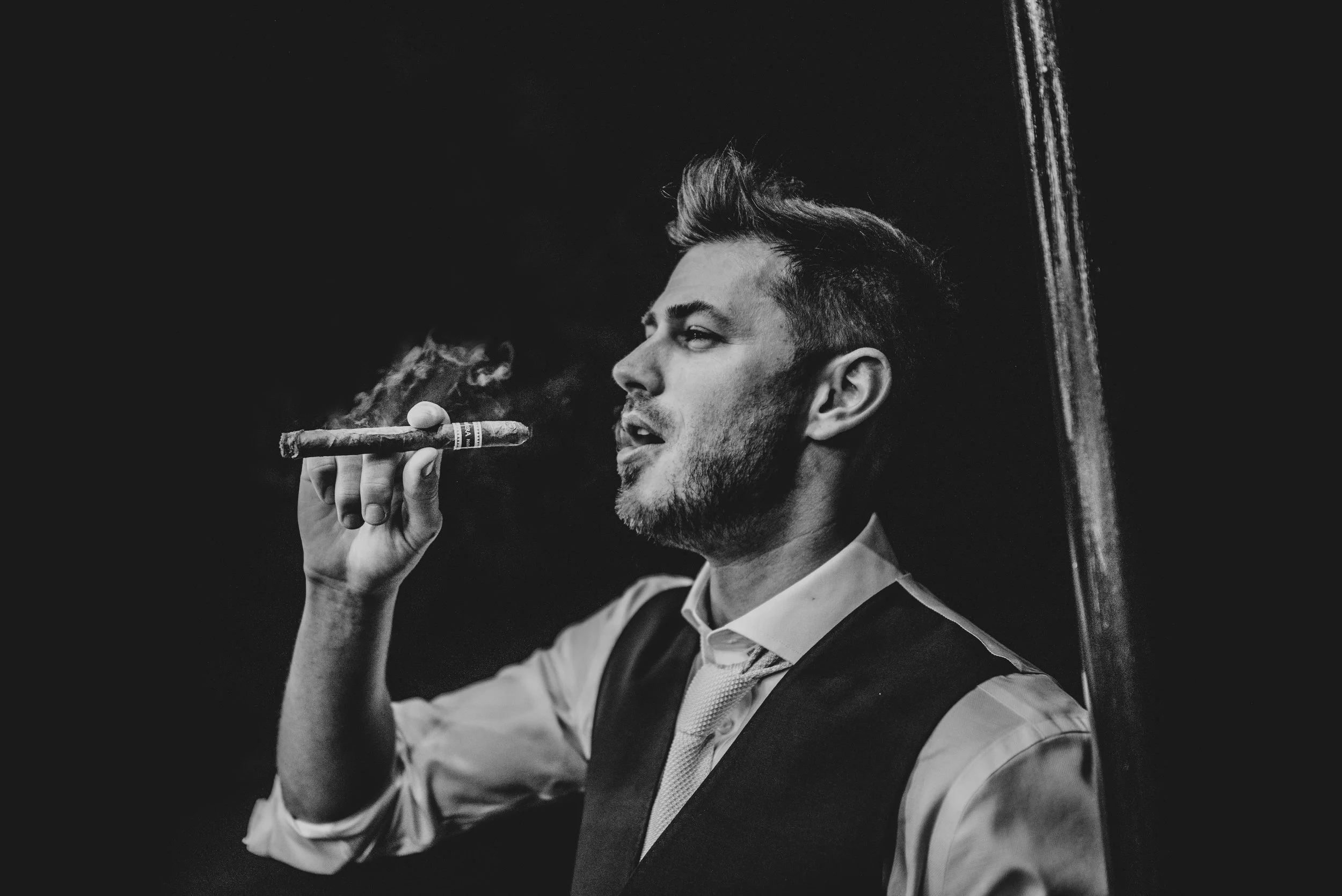 Groom smokes a cigar during evening reception at Channels Weddings Essex Documentary Wedding Photographer