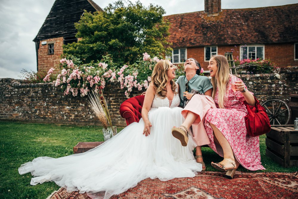 Lush, Vibrant Reds and Tweed for a Movie inspired Barn wedding at The House Meadow with Bridesmaids in Jumpsuits and a Festival Vibe. Essex Documentary Wedding Photographer
