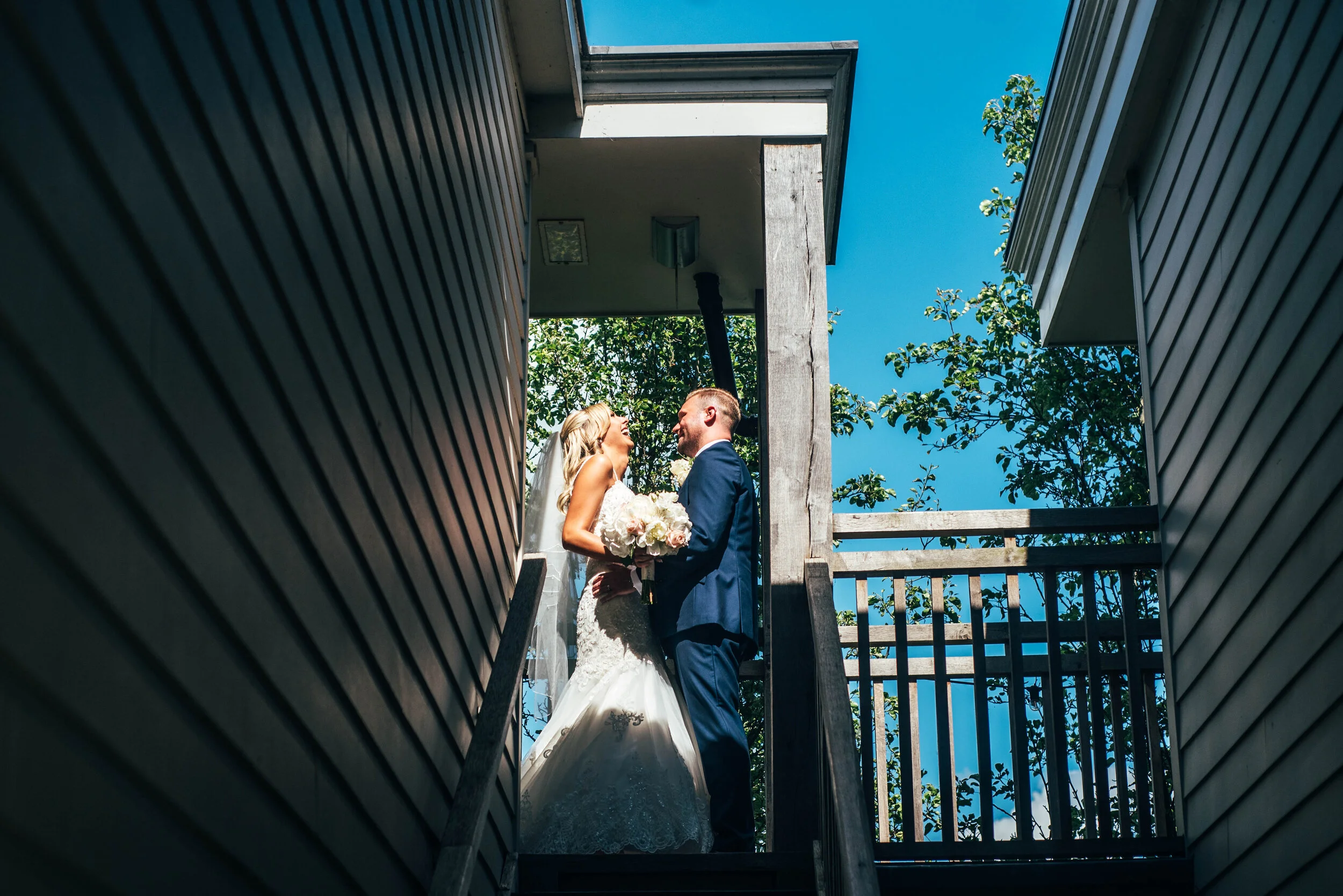 Bride & Groom in harsh light at top of stairs at The Lion Inn, Boreham. Essex documentary wedding photographer. Three Flowers Photography