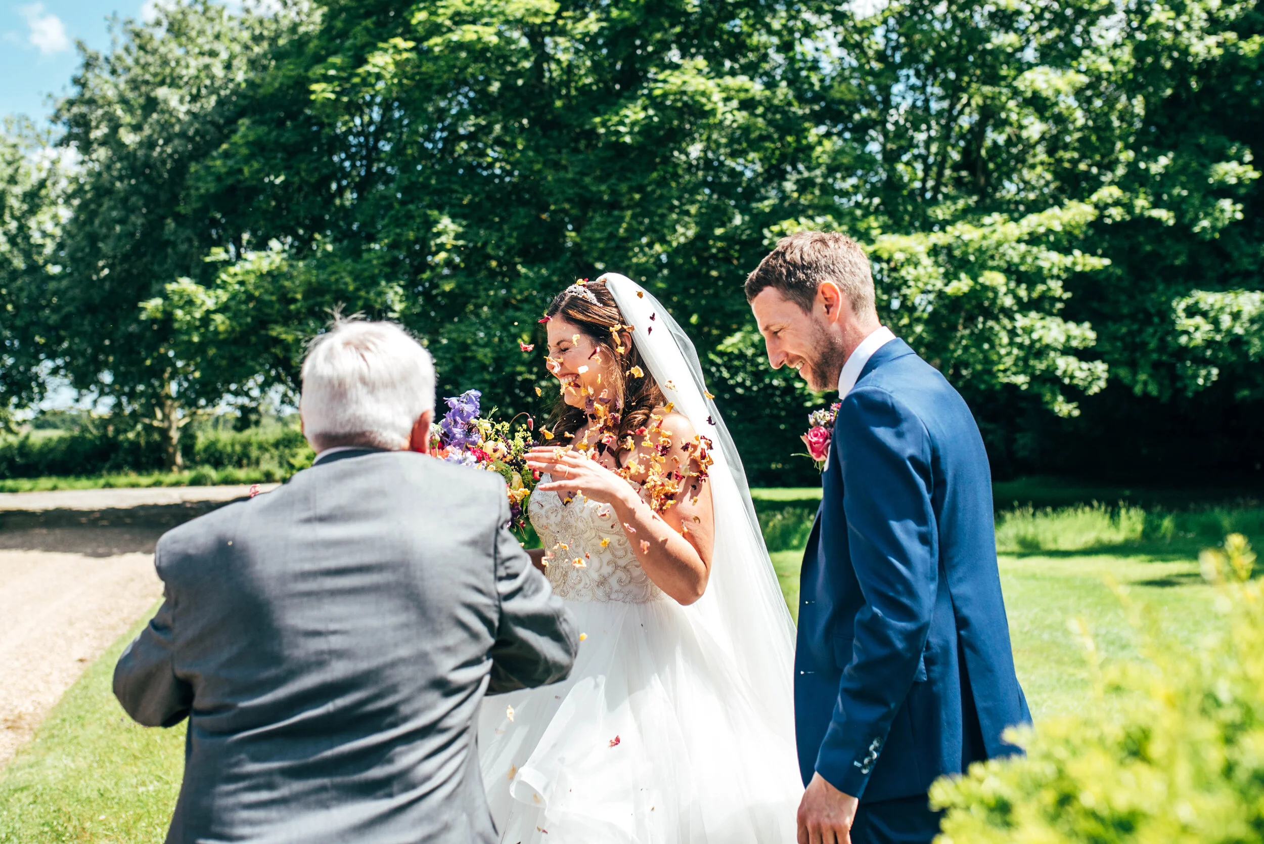Guest throw confetti in Brides face. Back garden diy tipi wedding. Essex documentary wedding photographer. Three Flowers Photography