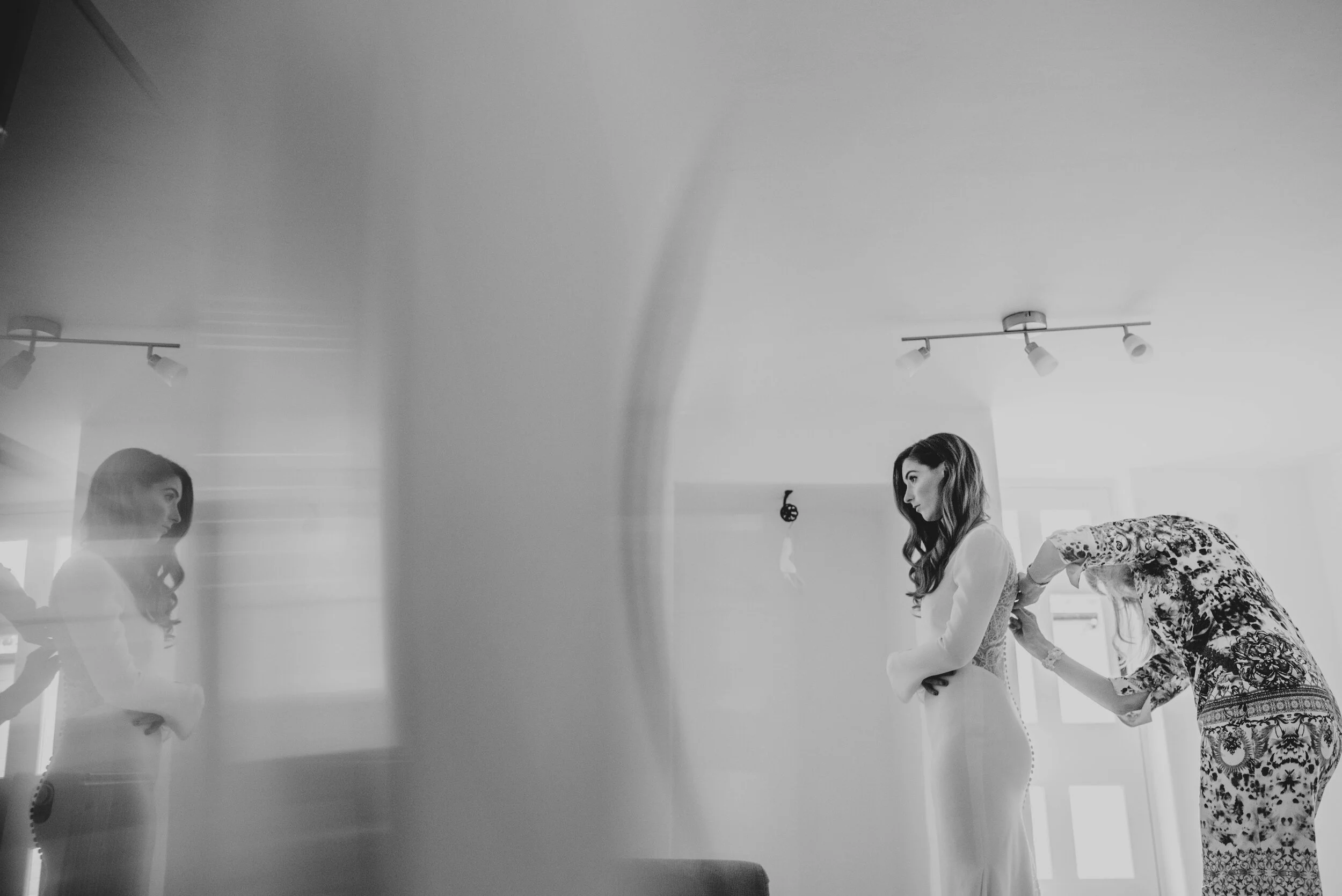 Bride's mum does up her dress with prism reflection at Blake Hall. Essex Documentary Wedding Photographer. Three Flowers Photography