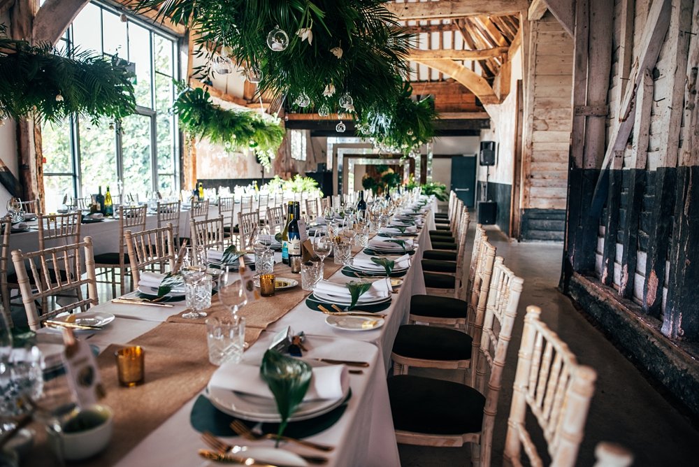 A festival inspired barn venue with lush foliage &amp; greenery leading the styling at Henham Weddings. Essex documentary wedding photographer.
