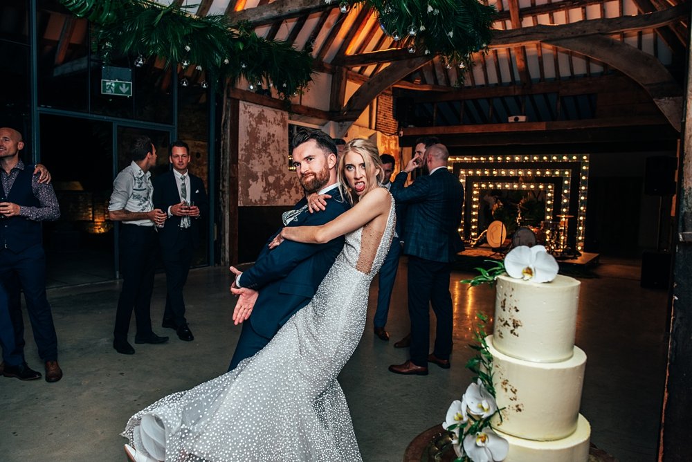 A festival inspired barn venue with lush tropical foliage &amp; greenery leading the styling at Henham Weddings. Essex documentary wedding photographer.