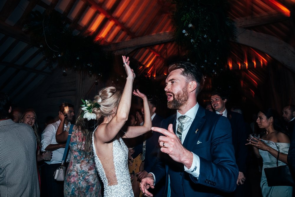 A festival inspired barn venue with lush tropical foliage &amp; greenery leading the styling at Henham Weddings. Essex documentary wedding photographer.