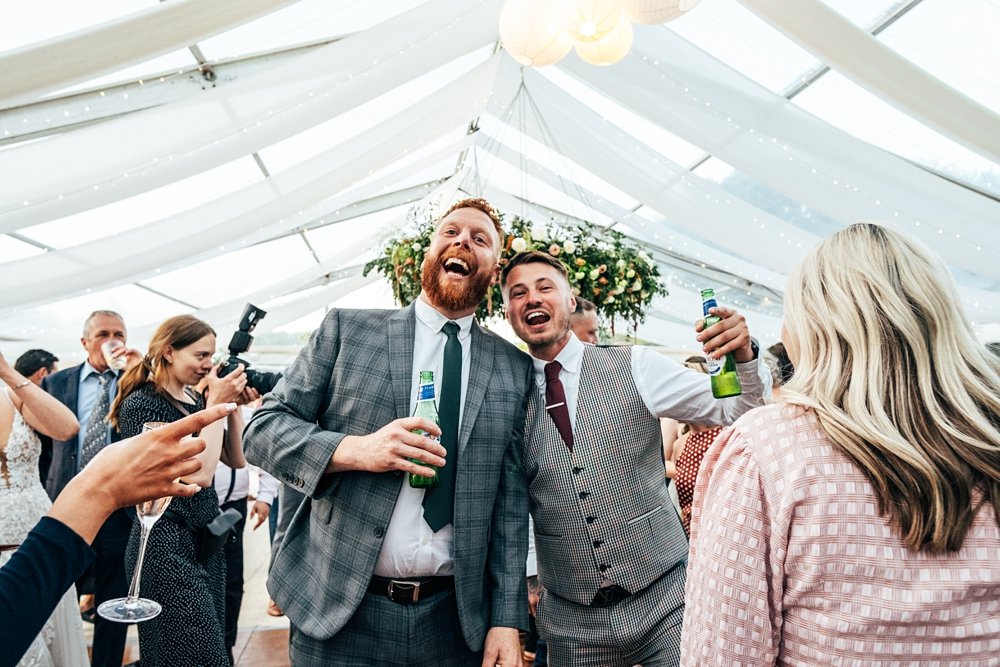 An outdoor, back garden, clear roof marquee wedding with statement Spring flower arch &amp; chandelier Essex documentary wedding photographer