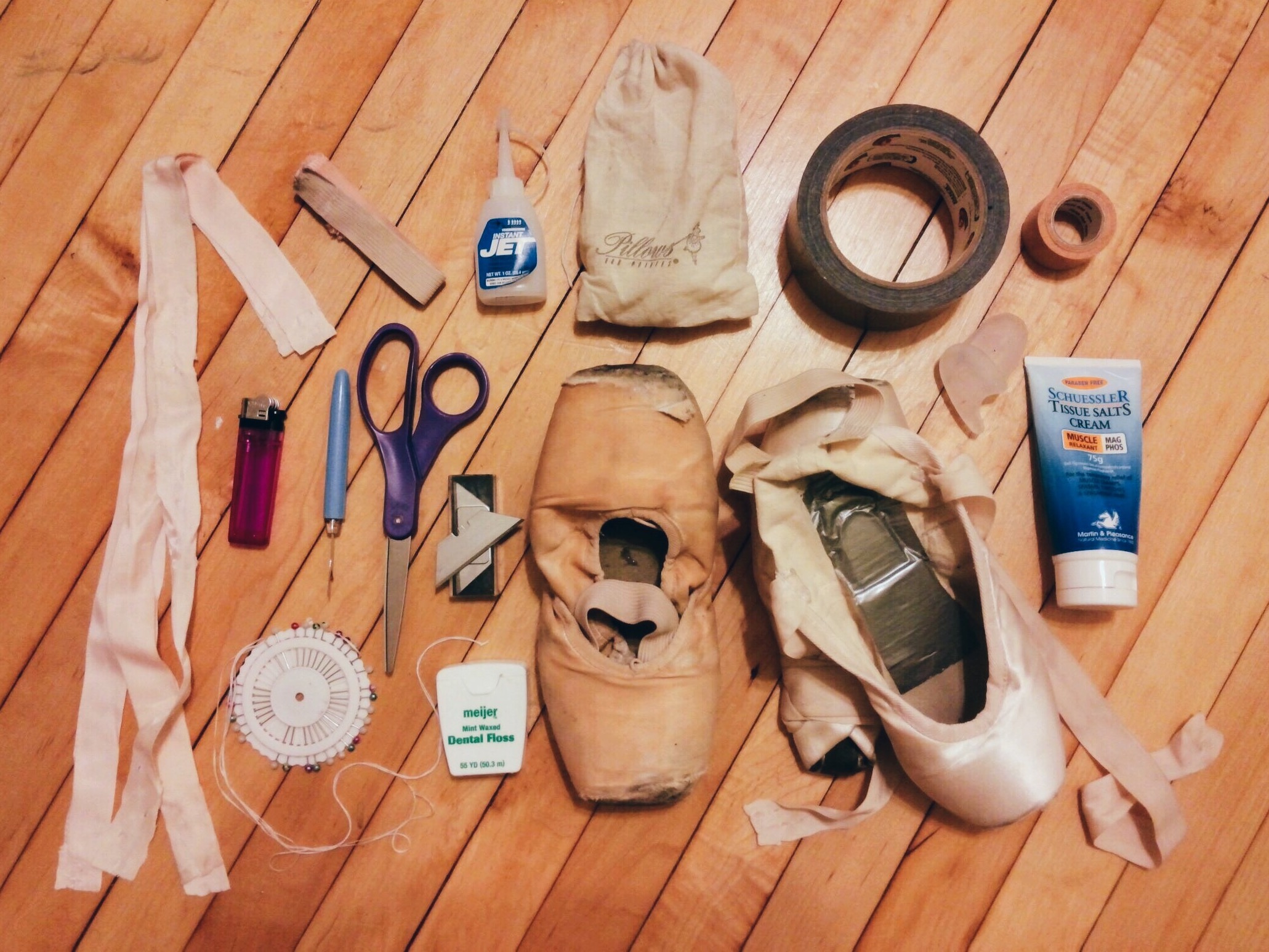 Laura Schlatter's Pointe Shoe essentials: (left to right) 1. Extra ribbons and elastics (I very rarely buy new ribbons & elastics), 2. Lighter (to burn edges of ribbons & elastics), 3. Needles & pins, 4. Seam Ripper, 5. Scissors, 6. Dental Floss (sometimes I use quilting thread), 7. Extra blades for my pocket knife (which was confiscated at airport security while on tour! Oops!), 8. Jet Glue, 9. Lamb's wool, 10. Shoes for both contemporary & classical repertoire (I only 3/4 shank my left shoe), 11. Duct tape - for my toes, 12. Toe spacers (sometimes when my bunion is hurting I will wear a toe spacer, but on rare occasions), 13. Squishy tape (I sometimes use this on my heels) 14. Muscle relaxant cream for my calves