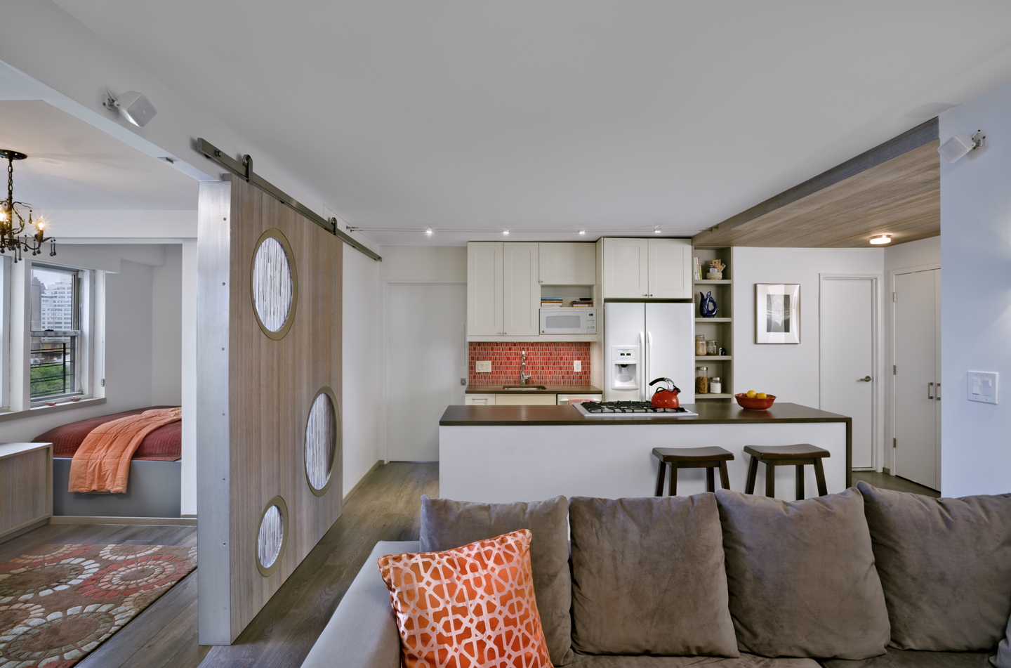 3 apartment combination multi generationl lving unit This apartment is an amalgamation of 3 studio apartments, one originally owned by a young couple with a small child and one owned by "his" parents. The apartments were separated by a third studio apt. which they recently acquired. When they acquired the middle apartment rodriguez studio was brought on to create an unusual living arrangement- keeping one apartment as a pied-a-terre and joining 2 for the young family's home. The apartment has one shared kitchen and one dining room, and has 3 full bathrooms. The pied-a-terre apartment can be closed off from the other two- though it is usually left open, the child’s room is the largest and most distant from the center of activity, and the parents sleep in an highly adaptable alcove off the living room. A large cypress and polycarbonate door cordons off part of the living to create a sitting room off the alcove for more privacy if needed. The kitchen dominates the plan and it acts as a gathering area placed centrally. The apartment features ample storage, two entrances, and a laundry room. The cypress is used strategically to provide a visual unity and to delineate areas within the large open plan.