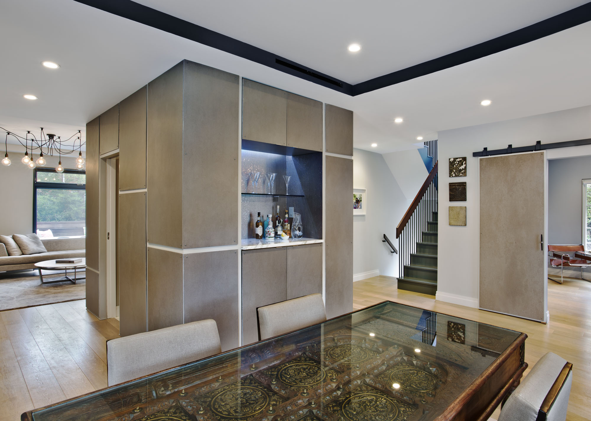 View of core and main stair from dining room. The core is clad in cement board and houses powder room, fireplace, and bar on main floor.