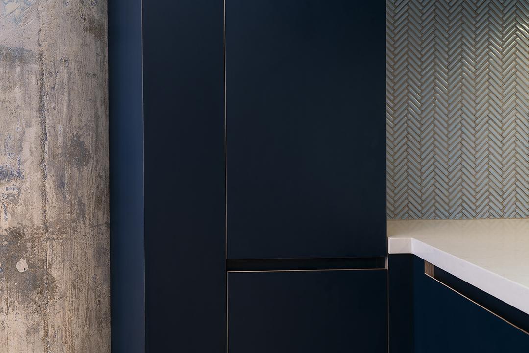 The knife edge detail on the lower cabinets reveals a glimpse of the plywood that lies below the surface, creating a striking contrast.