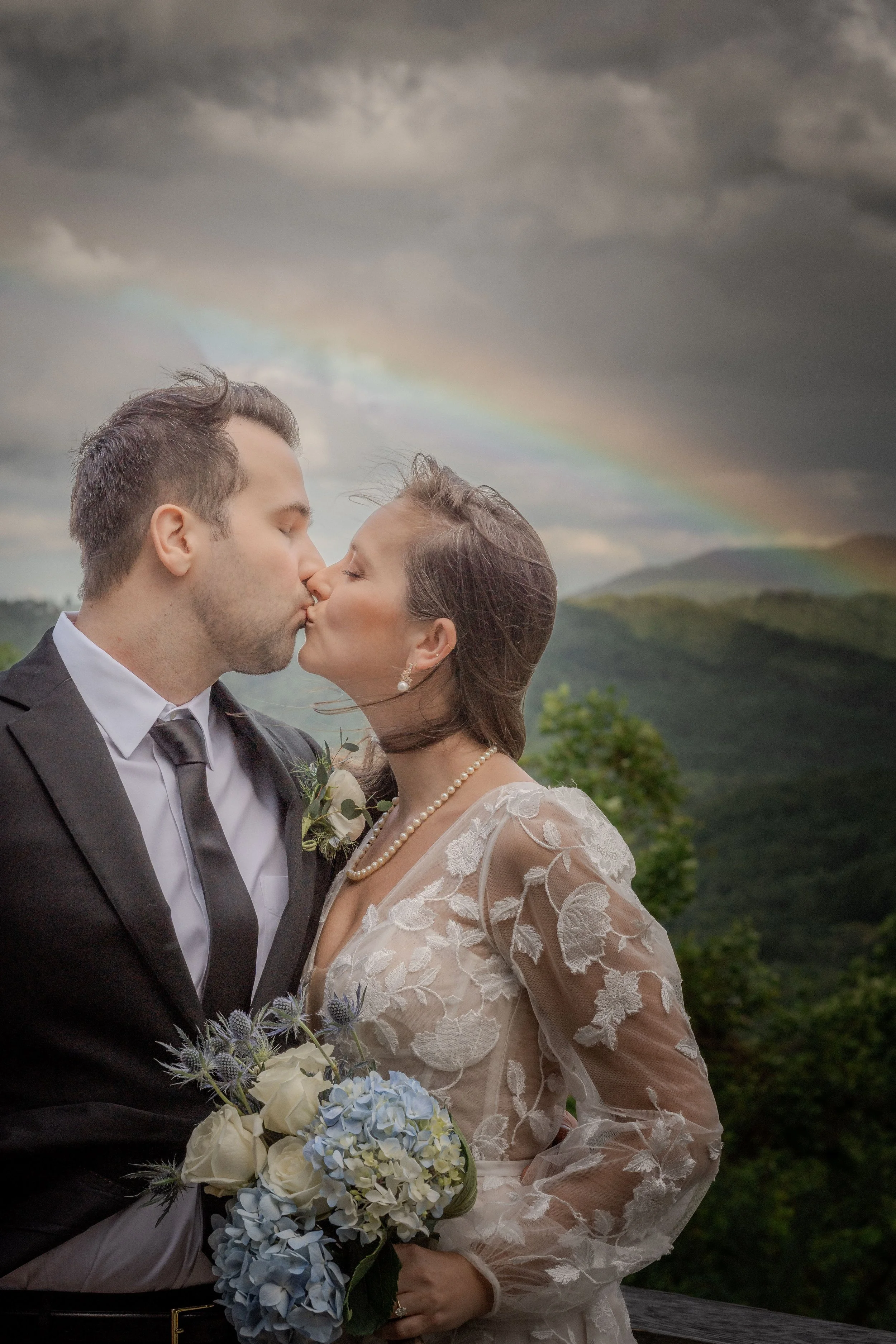 Bride and groom celebrating their wedding under a rainbow in the mountains of Western North Carolina