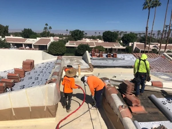 Roofing crew replacing residential tile roof and underlayment