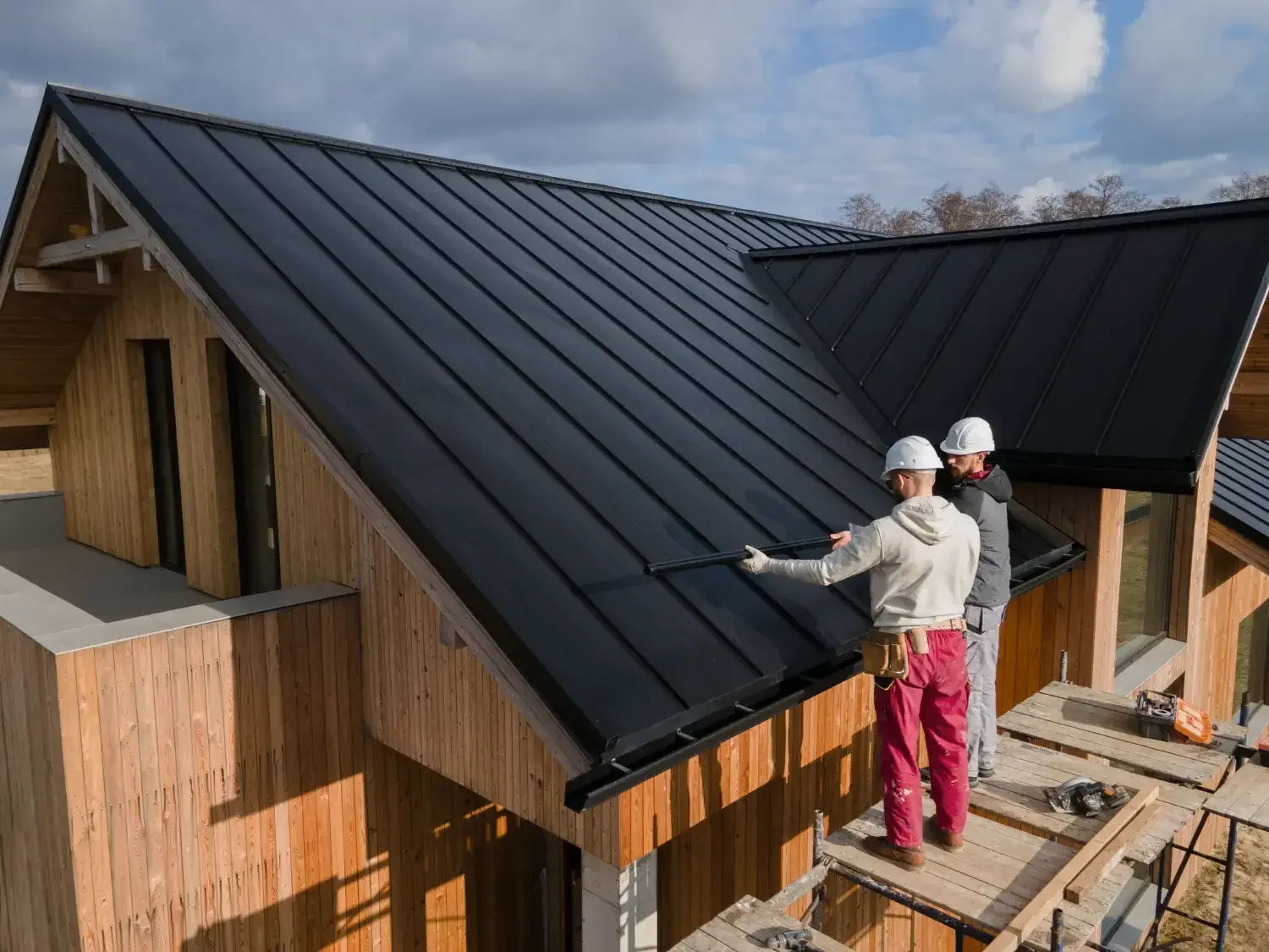 Metal roof installation on modern wood-clad home