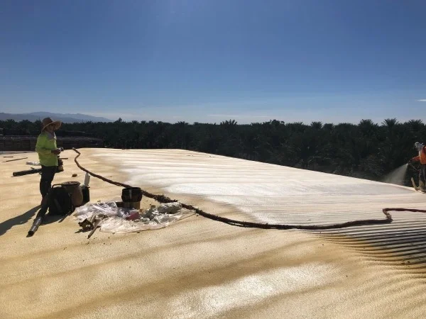 Contractors applying spray foam roofing on commercial flat roof.