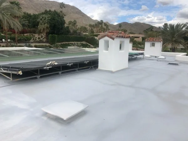 White flat roof with solar panels beside decorative chimneys.