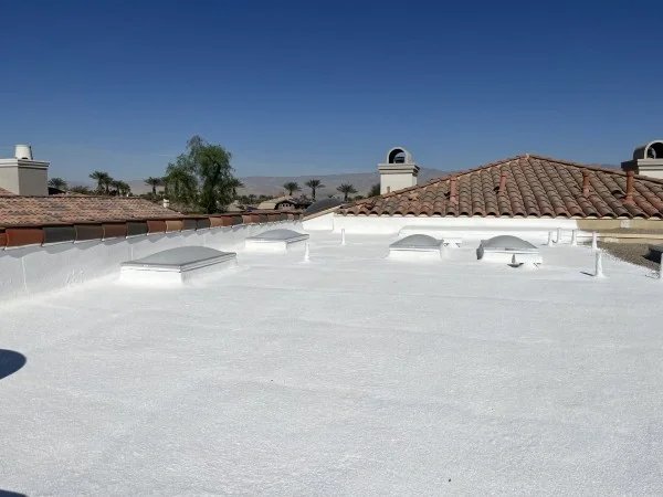 Bright white flat roof with skylights after foam roofing installation.