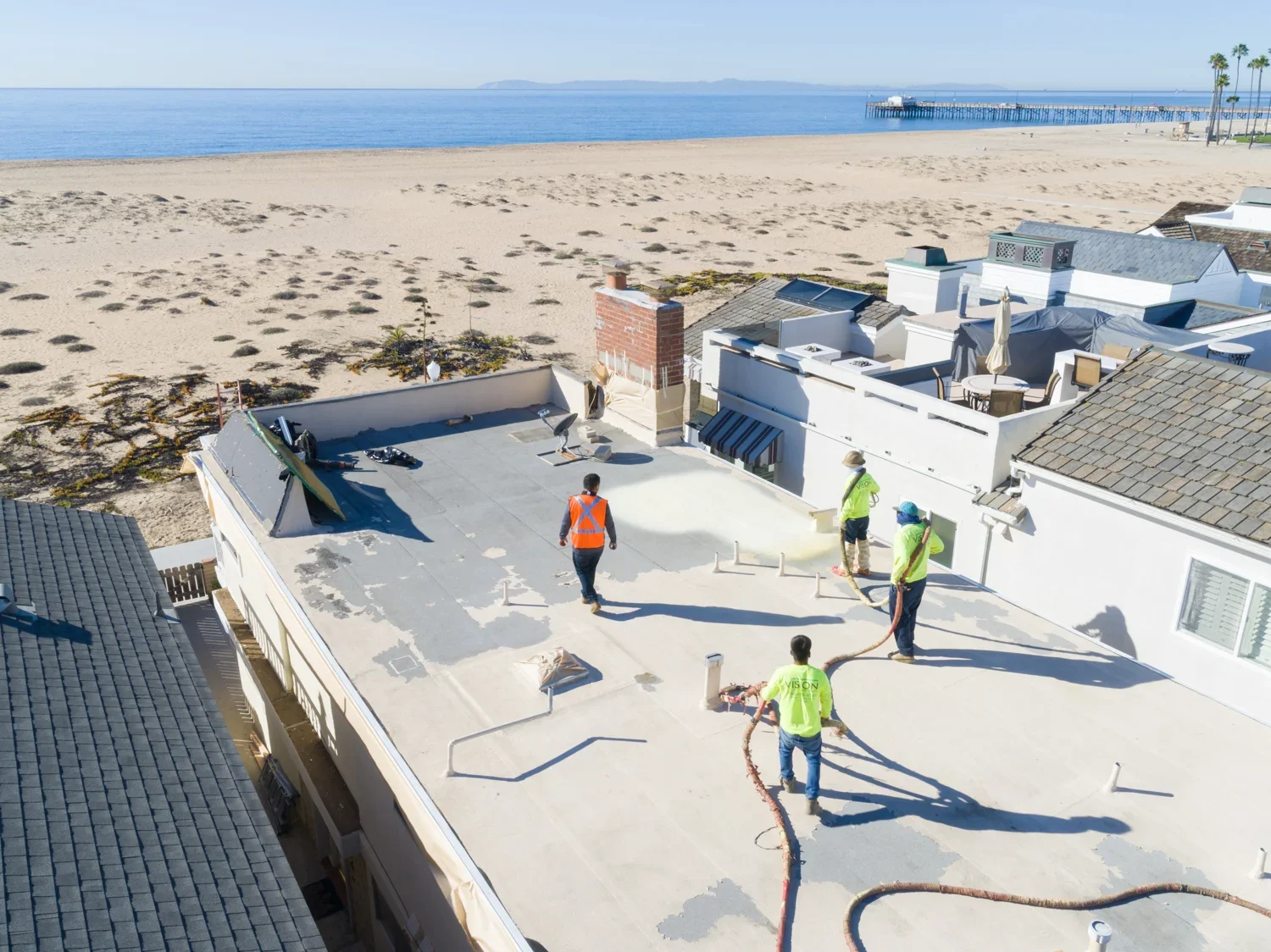 Roofing crew applying a protective coating to a flat roof