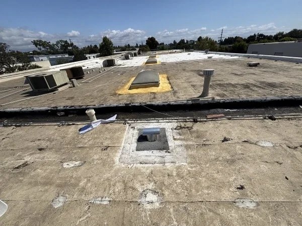 Aging commercial flat roof with vents and skylights
