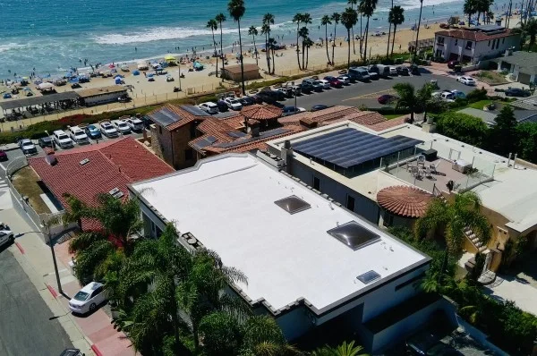 Coastal luxury home featuring modern flat roof and solar panels.