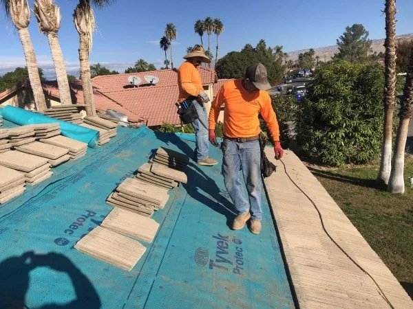 Roofing crew installing tile underlayment before replacing concrete tiles