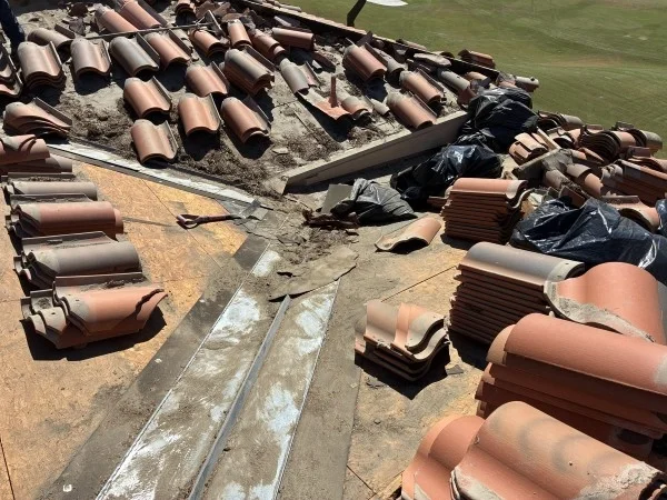 Clay tile roof replacement with removed tiles and flashing exposed.