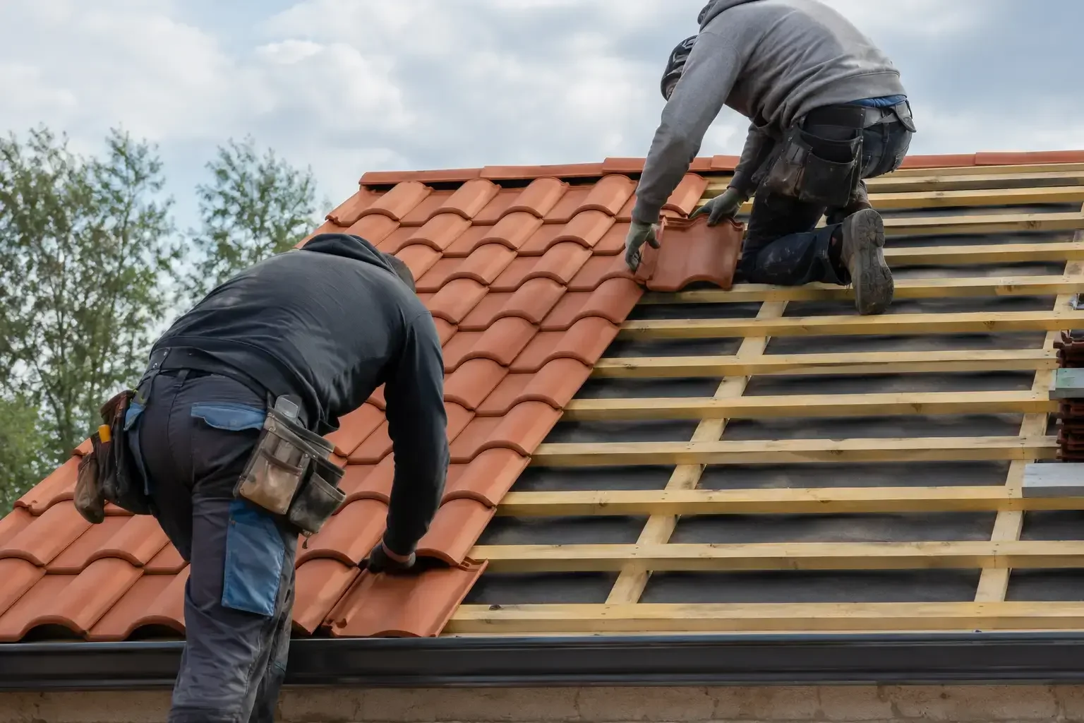 Roofers installing clay tile roofing system
