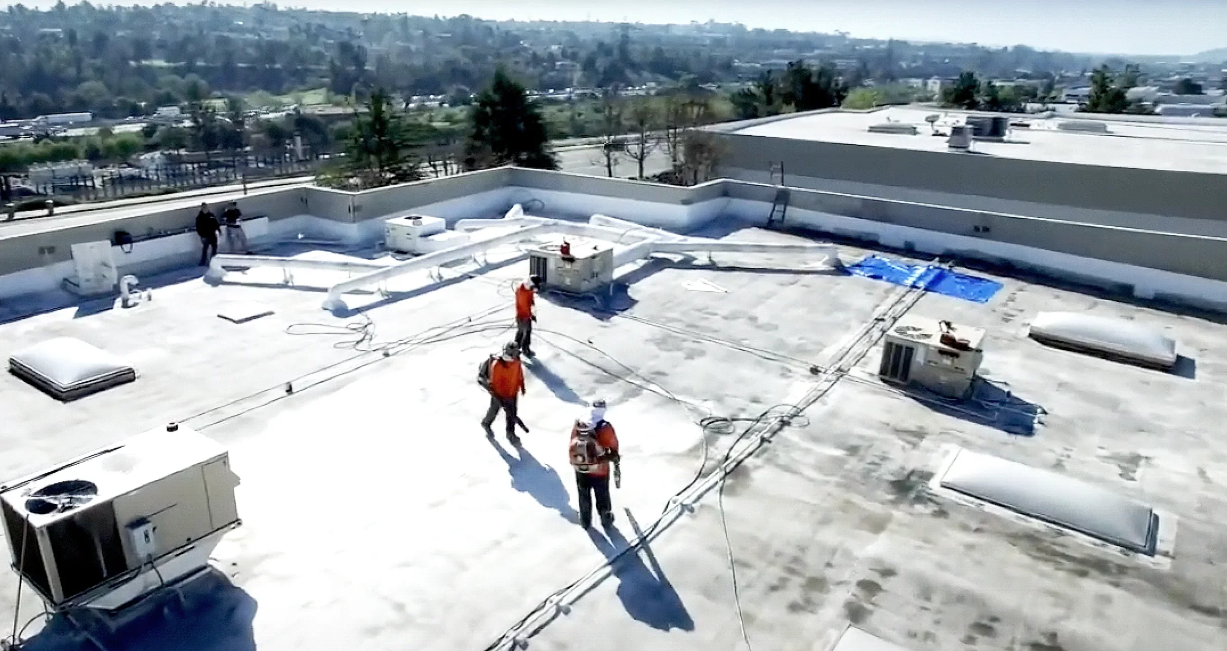 Crew applying spray foam roofing on a flat roof