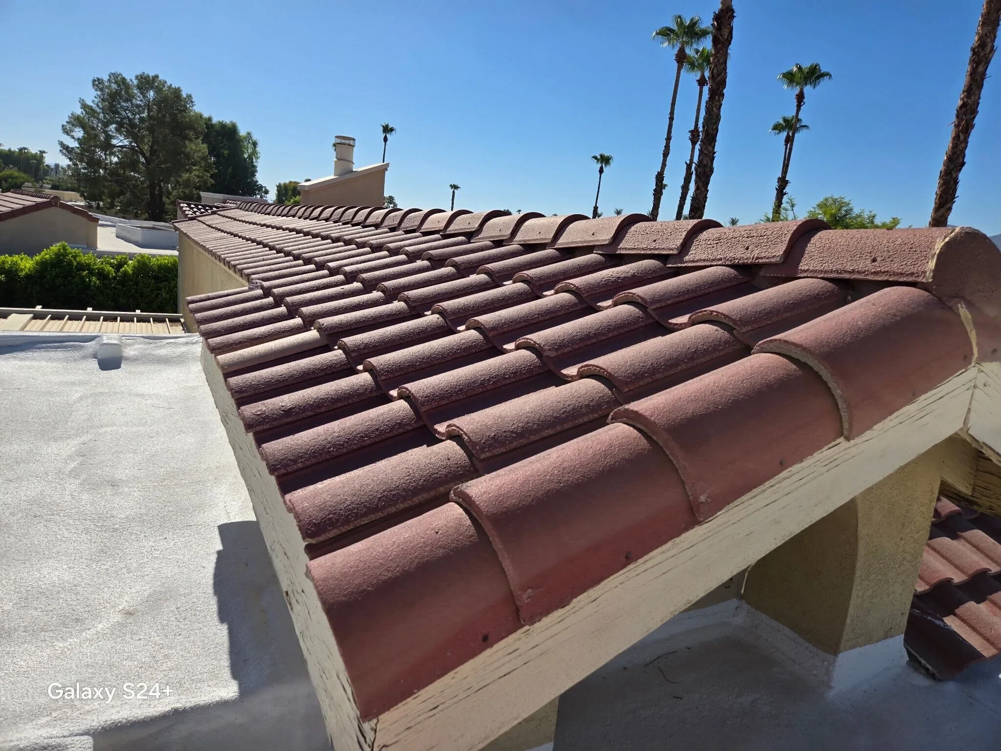 Red tile roof beside a coated flat roof