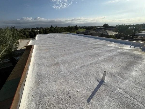Newly installed white foam roof overlooking desert mountain landscape.