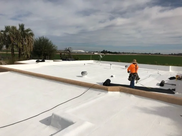 Spray foam coating applied across corrugated metal roofing system.