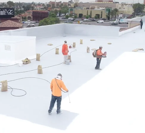 Crew applying reflective coating across commercial flat roof surface.