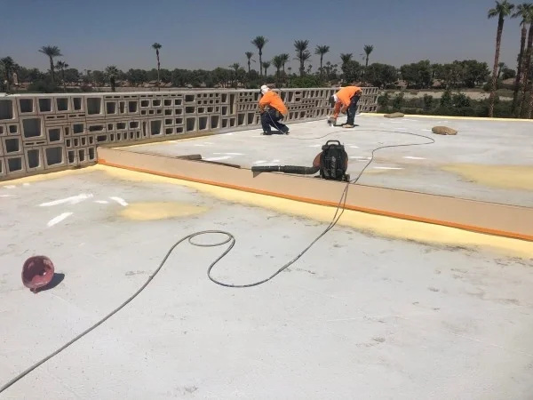 Roofing crew repairing coated commercial flat roof surface