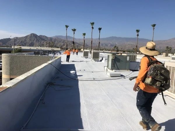 Crew applying protective coating across commercial flat roof surface.