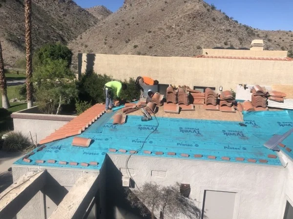 Roofing crew installing tile underlayment before replacing concrete roof tiles.