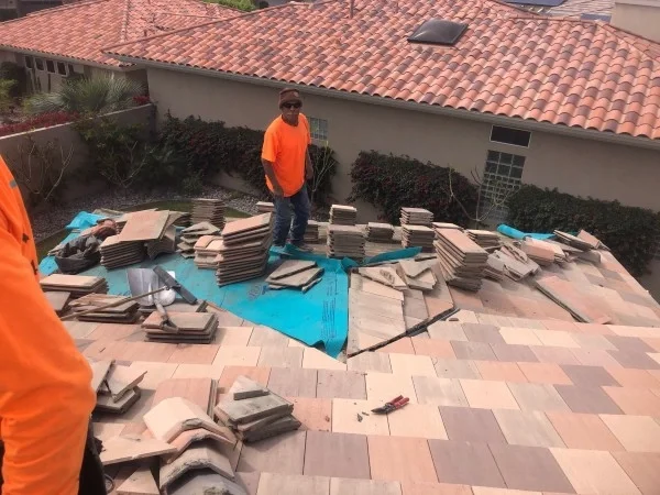 Roofer replacing tile roof over protective blue underlayment