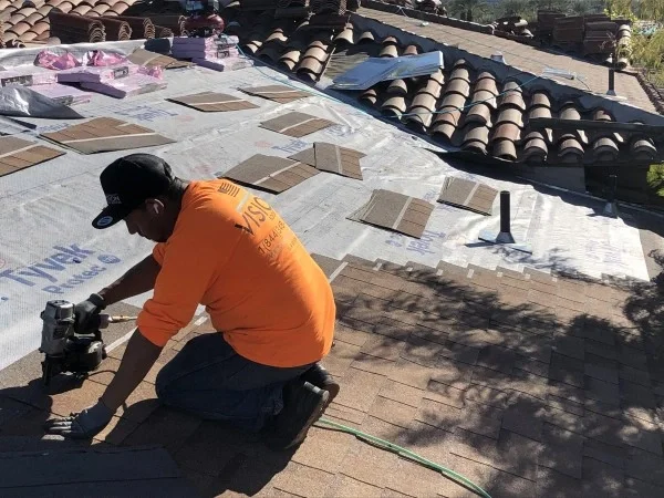 Roofer installing asphalt shingles over synthetic roof underlayment.