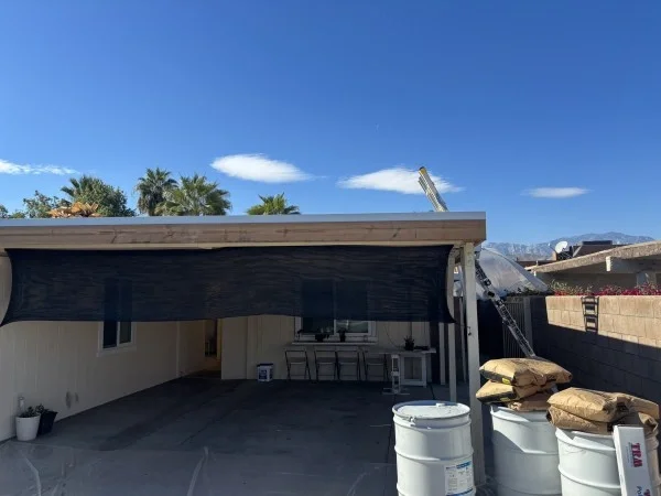 Covered patio beside home during residential roofing replacement project.