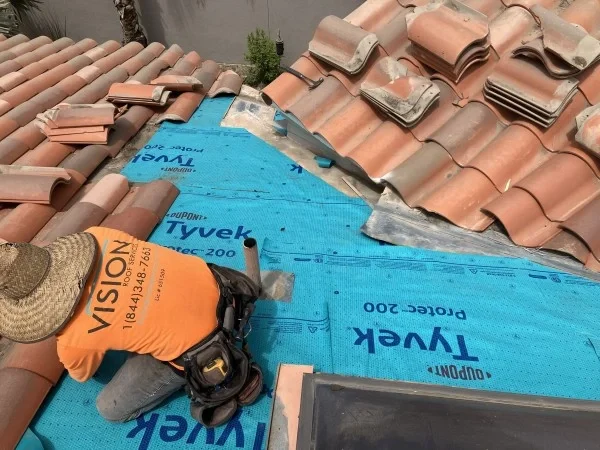 Roofer repairing clay tile roof over protective underlayment