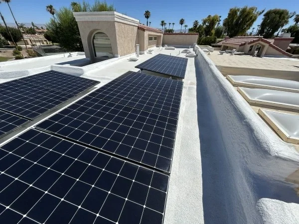 Solar panels installed on reflective white flat residential roof.