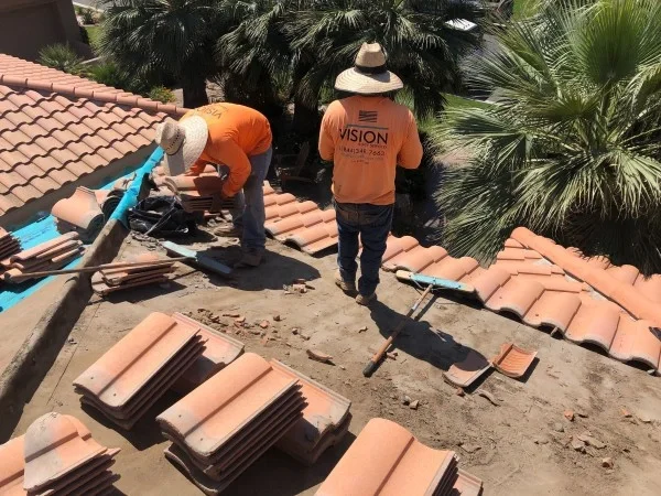 Roofers replacing concrete roof tiles during residential reroofing project.