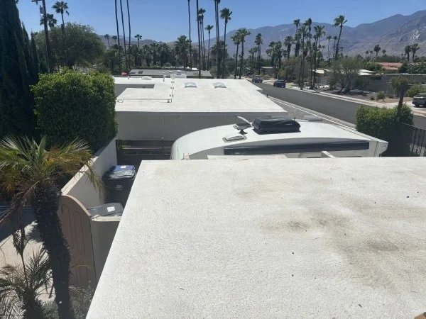 Weathered white flat roof requiring cleaning and protective coating.