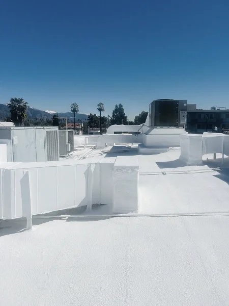 Fresh white roof coating surrounding rooftop mechanical equipment and ducts.